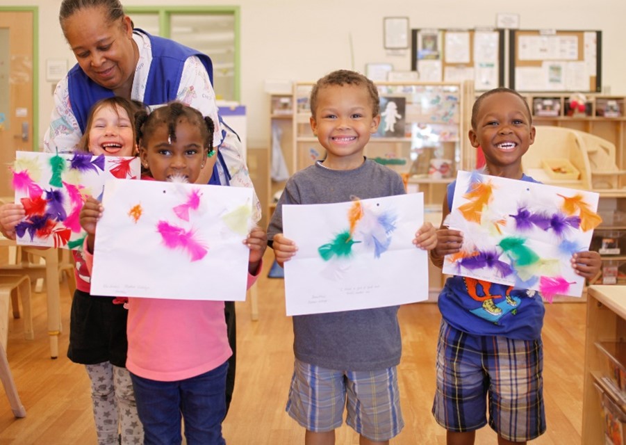 Children standing and holding handmade art work 