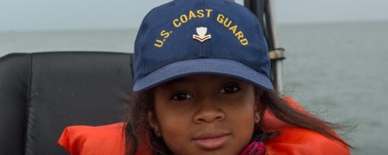 Young girl in Coast Guard baseball cap